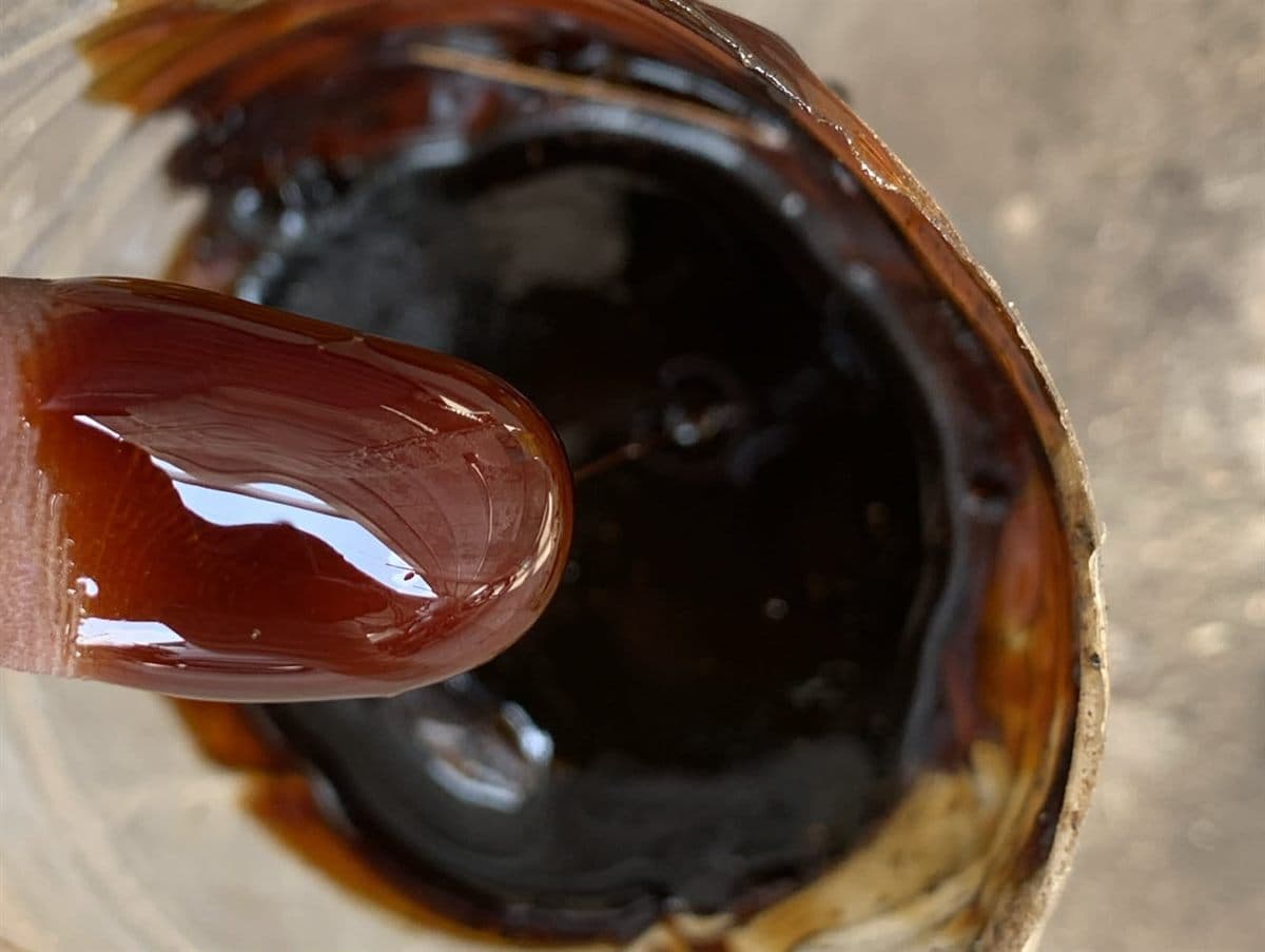 Liquid cane molasses for cattle feed — viscous dark amber syrup showing the characteristic colour and consistency of Grade A molasses used as a pellet binder and palatability enhancer in Indian compound feed manufacturing